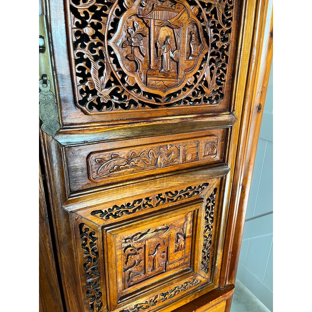 This is an antique Chinese carved wooden wedding cabinet dating back to the late 19th-century Qing Dynasty. It features...