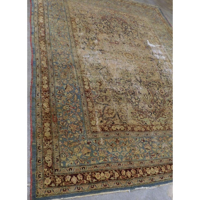 Distressed antique hand-knotted Persian Kerman decorative rug featuring a beige center field, ornate floral motifs, and a...