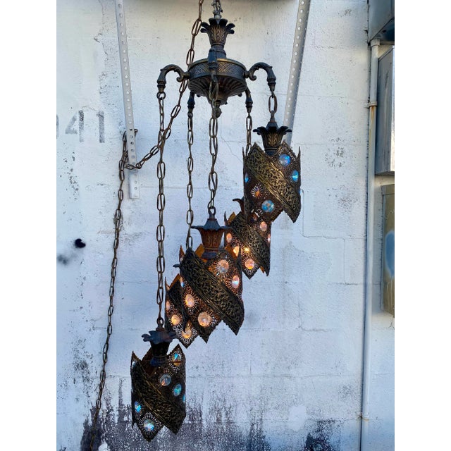 The chandelier features a center point with five hanging lanterns each with a different colored jewel.