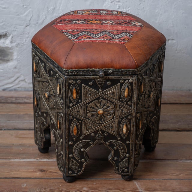 A pair of Moroccan stools with octagonal leather-upholstered tops and kilim centers. The hinged lift-top seats open to...