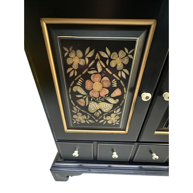 A beautifully crafted vintage cabinet by Ethan Allen, featuring a dramatic black painted finish accented with hand-painted...