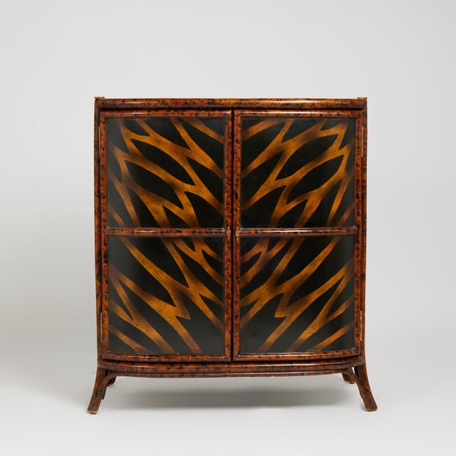 Standout mid century British colonial style handcrafted cabinet featuring a faux burnt bamboo frame with a bow front form,...