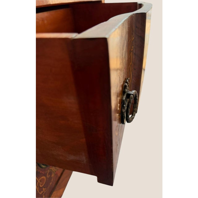 Decorative vintage Louis XV–style bombe commode featuring a gracefully curved three-drawer case, elaborate floral and urn-...
