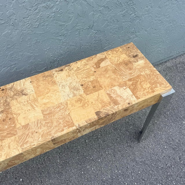 A striking Mid-Century Modern console table defined by its bold contrast of richly figured burlwood laminate and sleek...