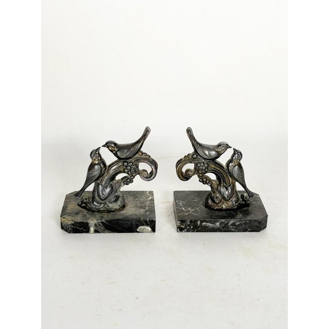 An elegant pair of 19th-century bookends depicting finely sculpted birds perched on decorative branches adorned with...