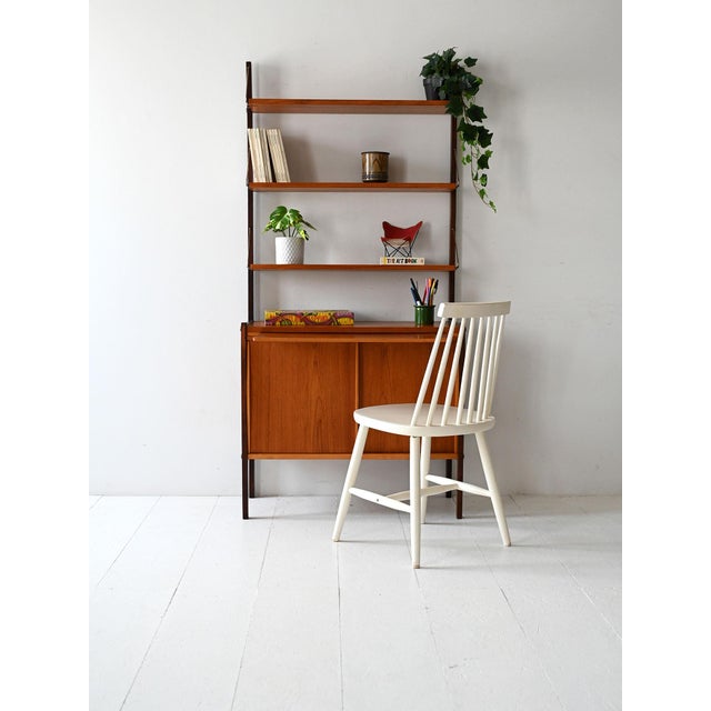 1960s bookcase with black painted wooden uprights, exposed shelves, sliding doors, and a pull-out desk. Late 1960s...