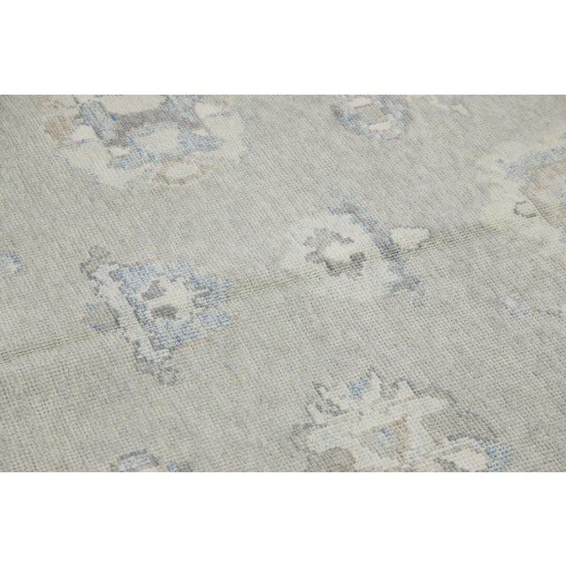 Elevate your interior decor with this exquisite Early 21st Century Gray & Blue Floral Design Handwoven Wool Turkish Oushak...