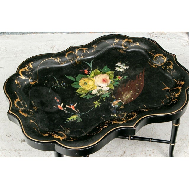 19th century polychrome black lacquer tole tray on stand or cocktail table. A shaped and hand-painted black metal tray...