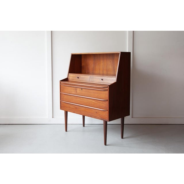 An exquisite teak bureau from Denmark, with three large and two small drawers, an open book shelf and a pull out table...