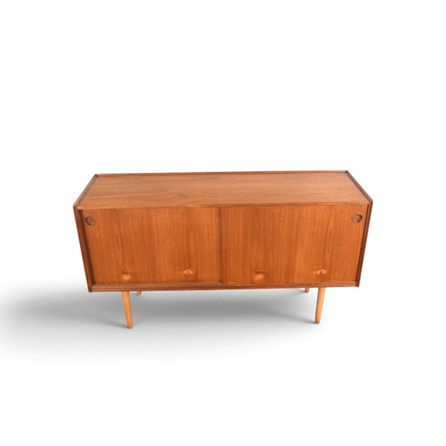 This credenza was designed by Arne Hovmand Olsen and produced by Mogens Kold in Denmark during the 1960s. The teak case...