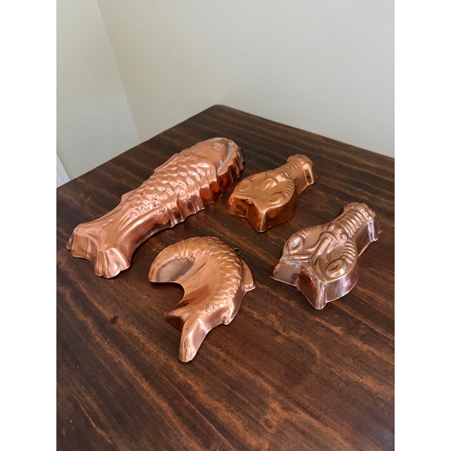 A charming collection of four vintage copper molds featuring fish and lobster forms, each retaining the warm glow and...