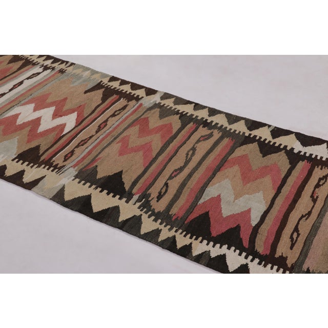 Made with handwoven wool circa 1950-1960, this 3x10 vintage flat-weave runner Kilim is a particularly dynamic and sought-...
