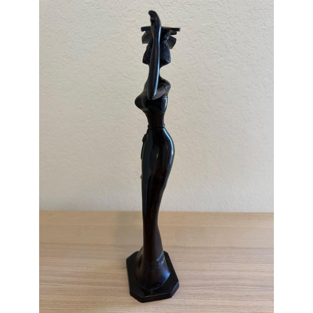 This beautiful African-inspired figurine features an elegant woman with an elongated silhouette, gracefully carrying a...