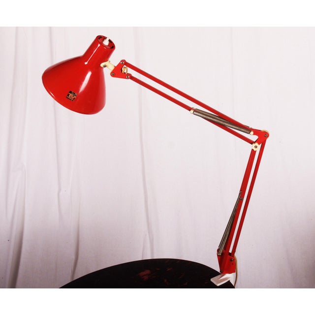 This lamp that is attached to the side of a desk was produced by Luxo in the 1970s. It is made from red lacquered steel...