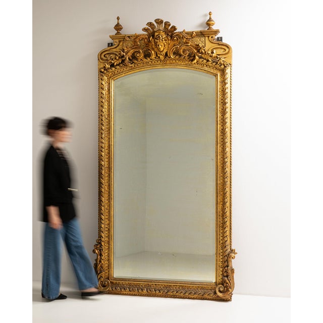 This piece presents as a mirror, distinguished by gold gilt ornate frame with crest, tall. It was made in France during...