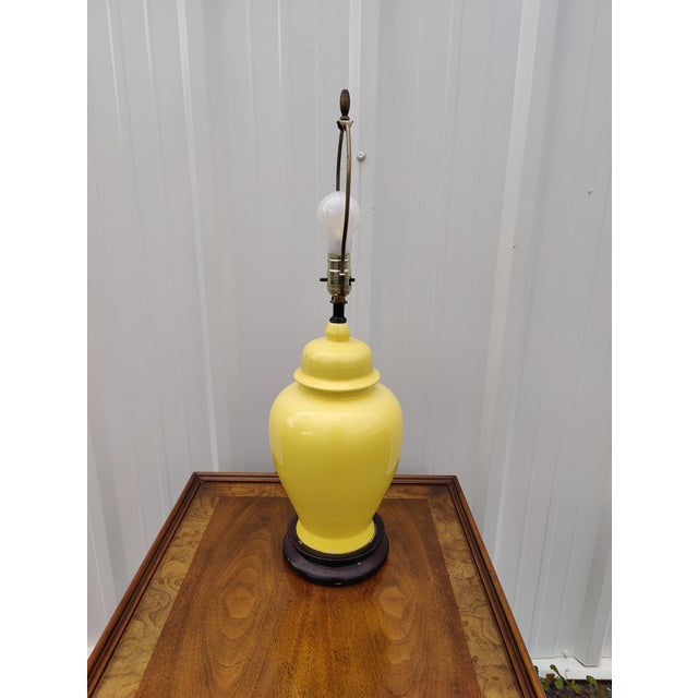 Vintage Mid-Century pair of yellow Chinoiserie style ginger jar porcelain table lamp with black base. The lovely lamp will...