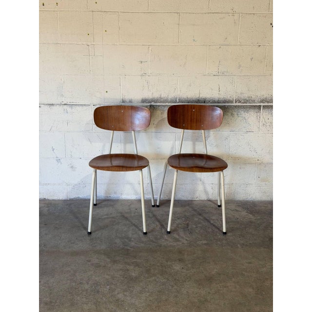 These versatile stacking chairs feature contoured plywood shells paired with sturdy white tubular steel frames. Their...
