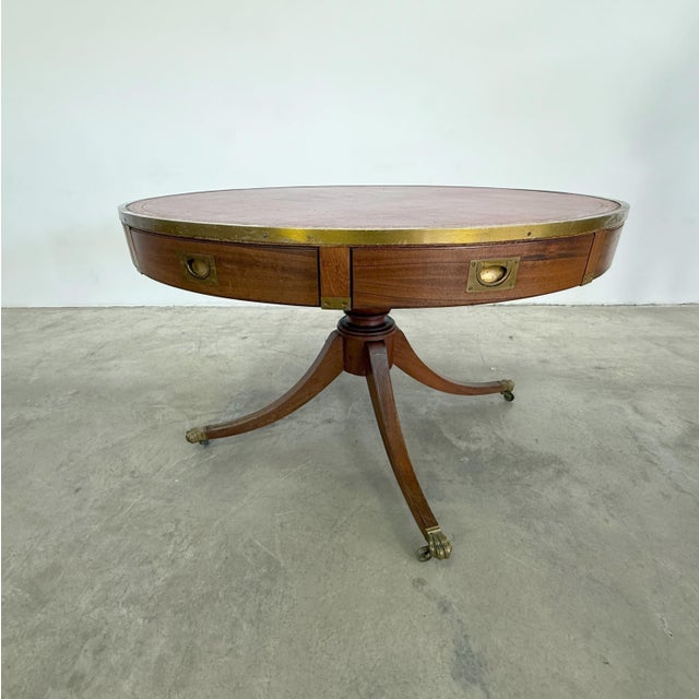 Dimensions: H 29.5” x W 47” Antique Regency style mahogany pedestal drum table with original red leather top and 4...