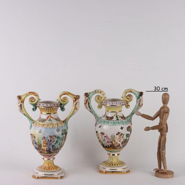Pair of Capodimonte ceramic vases with relief decorations depicting mythological scenes. Taken in the shape of female...