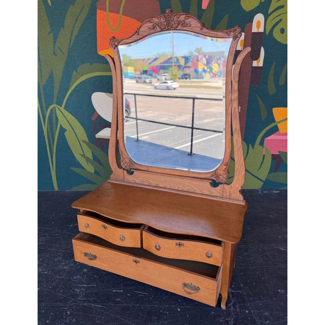 Early 1900s oak vanity with hand-carved mirror. This is a great size with the lower table height and statement mirror....