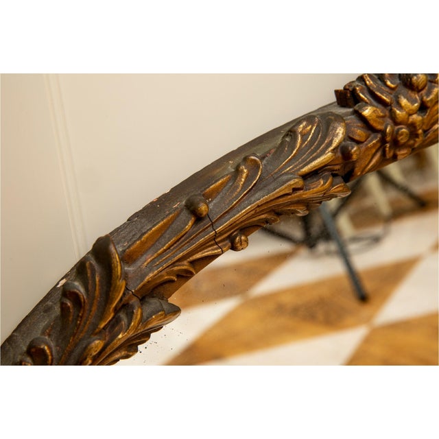 A large gilded Rococò-style mirror with an ornately carved wood frame, shell crest, floral sprays and scrolling acanthus...