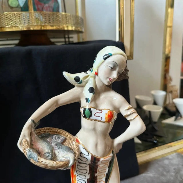 The ceramic figure has a sleek, elongated body with an elegant, somewhat abstract form typical of mid-century modern...