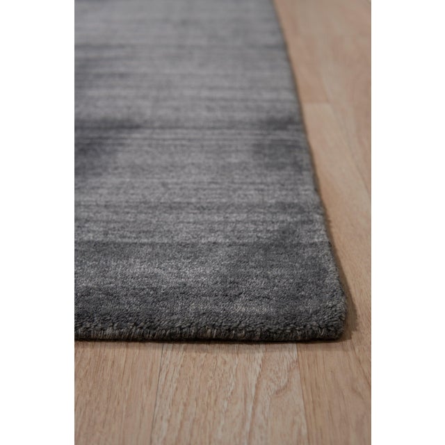 A 12' x 15' hand-knotted wool and viscose rug with a charcoal gray strie field with fine tonal streaks, in wool with...