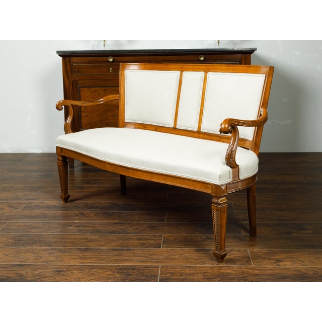 An Italian walnut settee from the 19th century, with curving back, scrolling arms and tapered feet. Created in Italy...