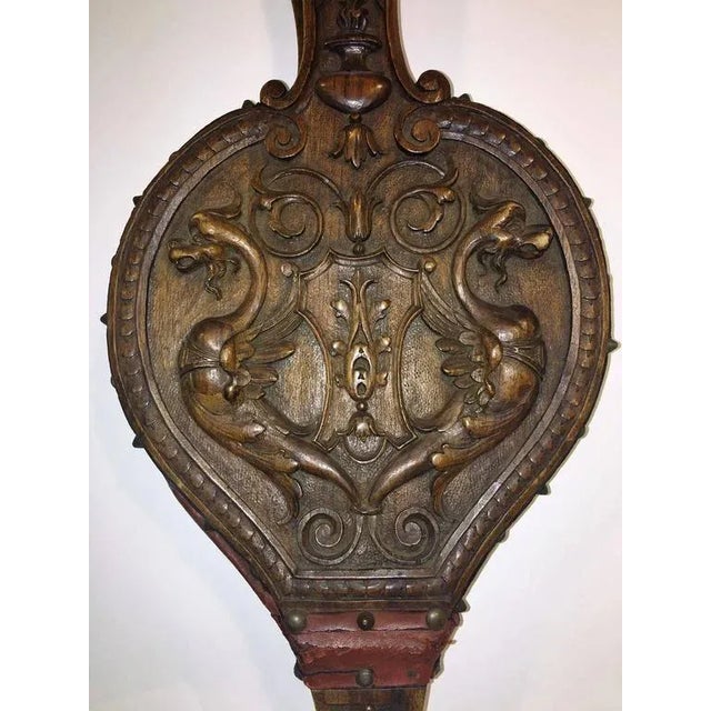 Intricately carved Italian fire bellows decorated with winged gri ns, roaring lion head and torch and coat of arms and on...