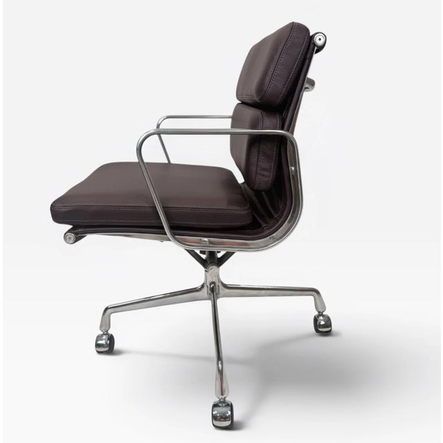 A classic Eames Aluminum Group Soft Pad Management Chair, upholstered in rich dark burgundy leather. The leather is...