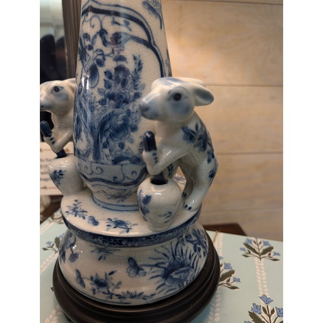 A charming and highly decorative vintage blue-and-white porcelain table lamp featuring figural rabbits posed atop petite...