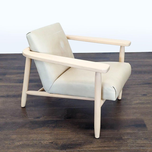 This Four Hands lounge chair features a stylish light wood frame and soft cream upholstery. Its wide seat and angled back...