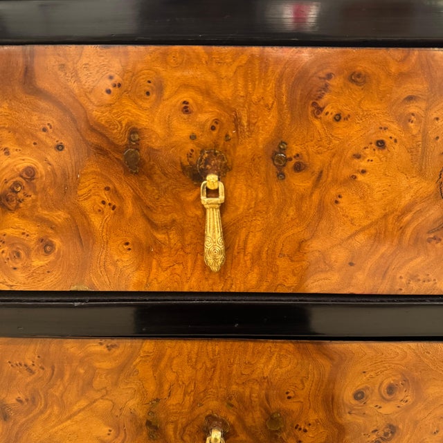 A small Art Deco chest of drawers. Amboyna and ebonized fruitwood with fluted leg details and patinated brass pulls.