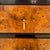 A small Art Deco chest of drawers. Amboyna and ebonized fruitwood with fluted leg details and patinated brass pulls.