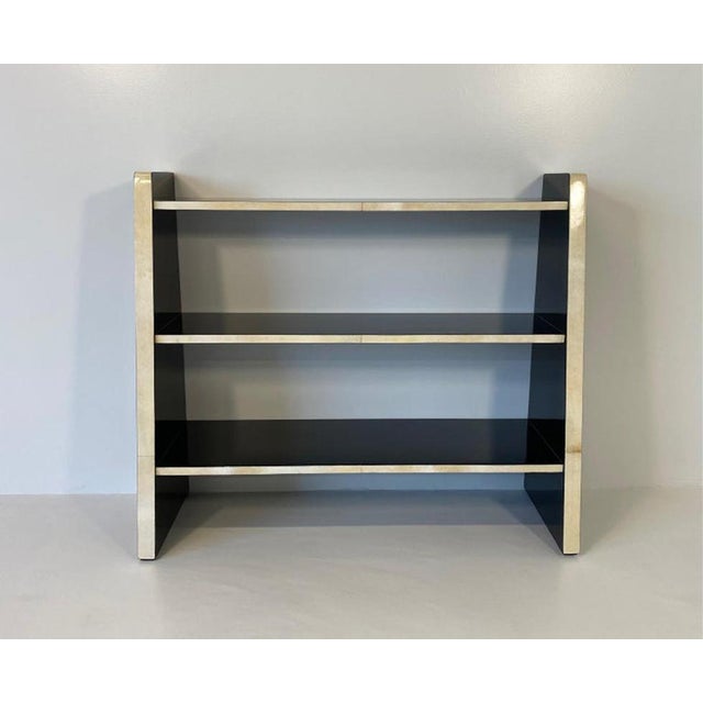 Elegant Italian bookcase from the 1980s, distinguished by a refined contrast between natural parchment and glossy black...