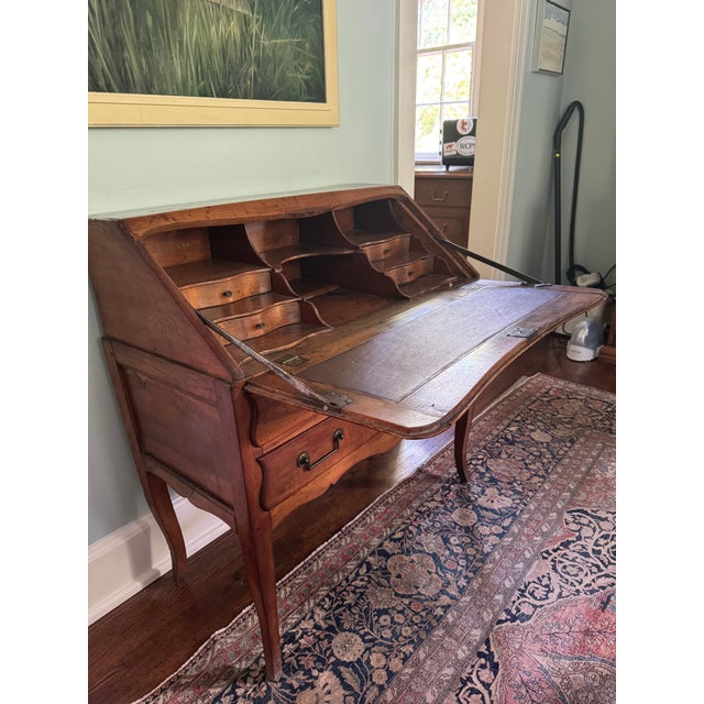 Charming antique slant-front secretary desk featuring solid wood construction, cabriole legs, and a warm reddish-brown...