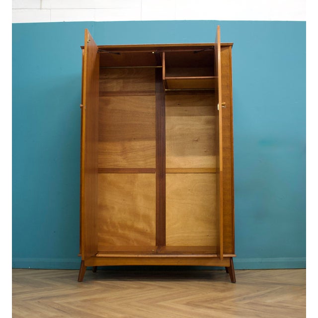 A stylish mid-century walnut wardrobe by Alfred Cox, featuring beautifully figured ripple walnut veneers, tapered legs and...