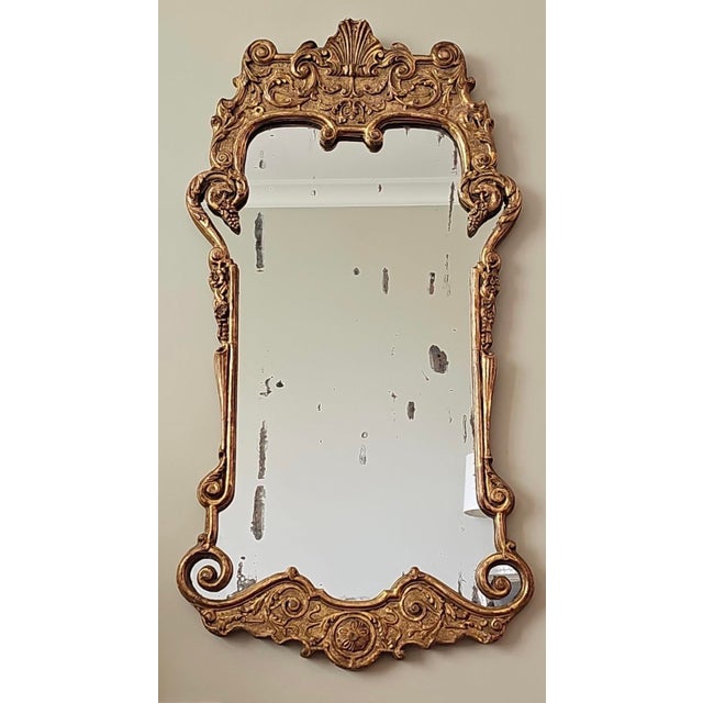 This is a substantial and beautifully ornate Rococo Revival giltwood wall mirror with a richly carved shell cartouche...