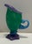A green and violet blown glass cream pitcher, on a petal shaped base with a swirling blue handle. Signed "AC," several...
