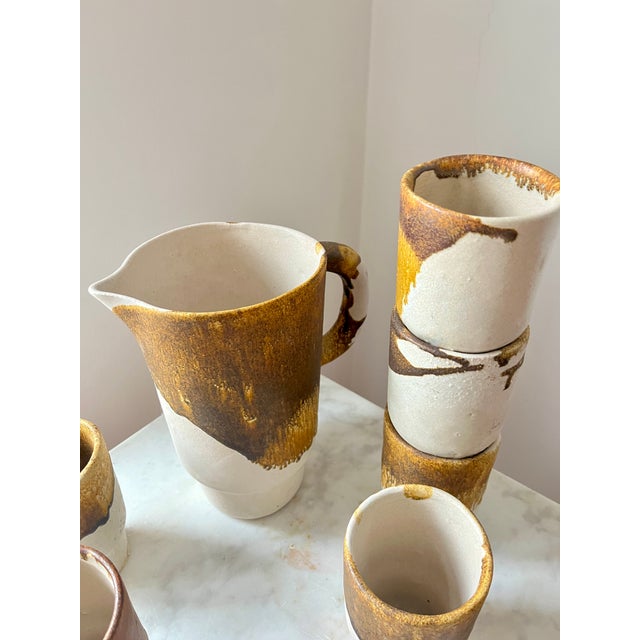 Authentic vintage mid-century studio pottery set including a pitcher, cups finished in a rich brown drip glaze over matte...
