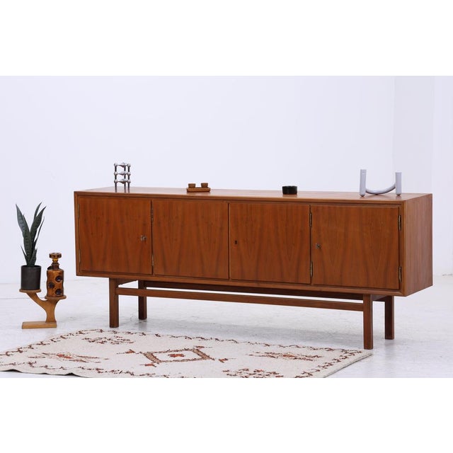 An elegant 1960s sideboard with a warm walnut finish, clean lines, and refined proportions. The integrated bar compartment...