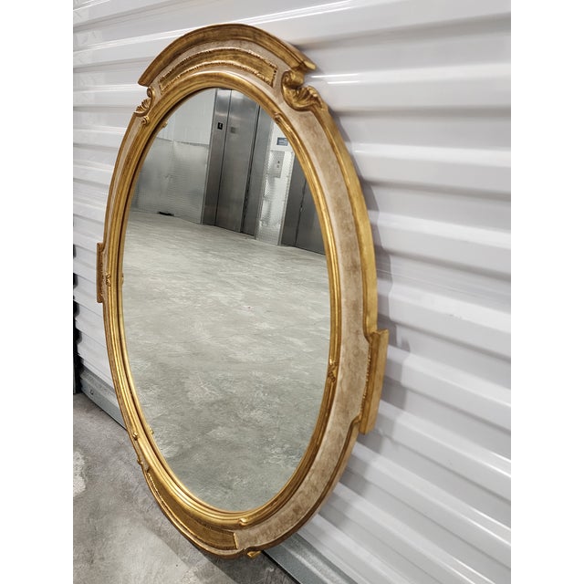 A distinctive carved wood oval form mirror by Carver's Guild in the Neoclassical style. The Newport mirror is painted in...