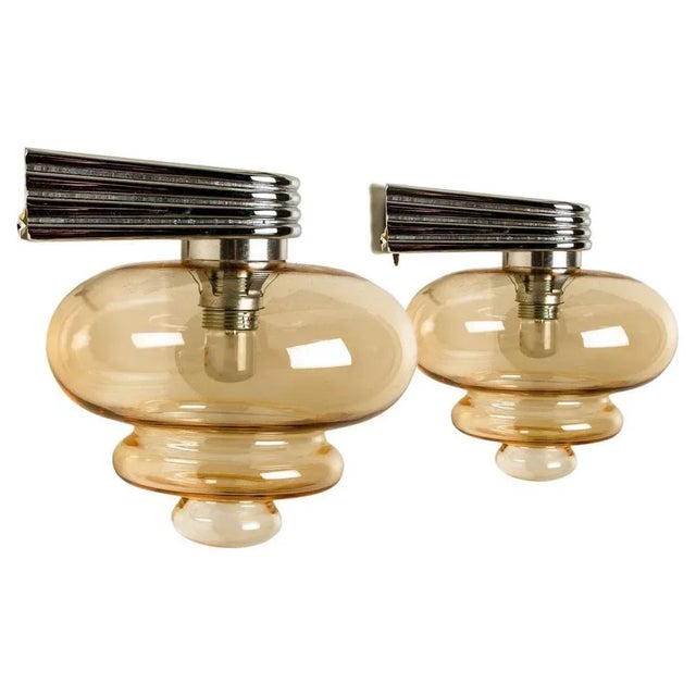 A pair of amber glass wall lights, made around 1970s. With a chrome fixture and 3 spheres shaped glass. The beautiful...