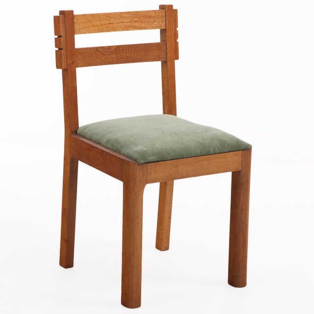 A striking set of six French solid oak dining chairs, attributed to Charles Dudouyt, circa 1945. Designed with a robust,...
