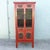 Striking vintage Chinese cabinet crafted in wood with a rich red painted finish, contrasting dark lattice doors, and...