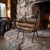 Sculptural black wrought-iron firewood holder featuring a folding X-frame, gracefully arched sides, and four elongated...