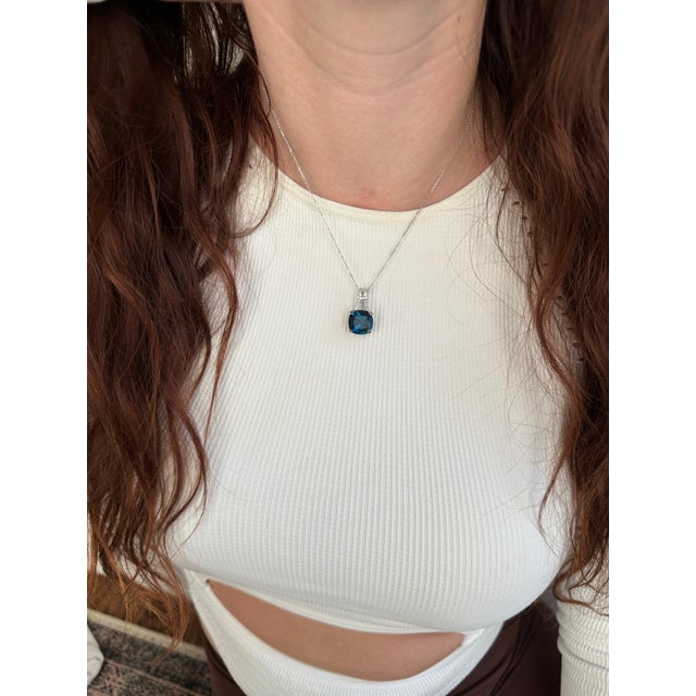 A london blue topaz glows with blue brilliance at the heart of this cushion pendant, framed by a trail of brilliant...