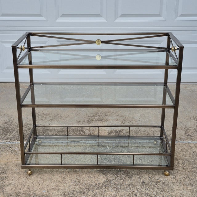 This is a stunning neoclassical style metal and glass bar cart or serving cart after Maison Jansen. The cart has a metal...
