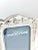 An elegant vintage silverplate picture frame featuring detailed repoussé decoration with bows, floral swags, and scrolling...
