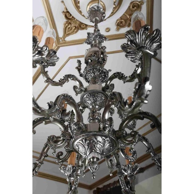 Heavy chandelier made of cast white brass with figural and floral decoration. The chandelier is restored. Restored...